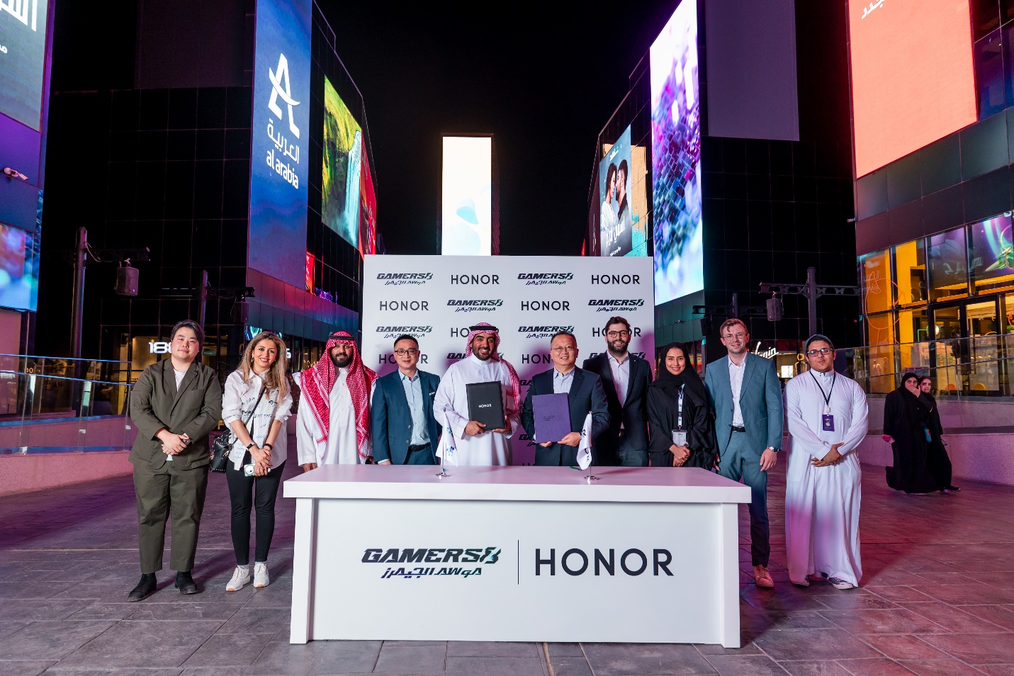 A group of people standing in front of a white table

Description automatically generated with medium confidence